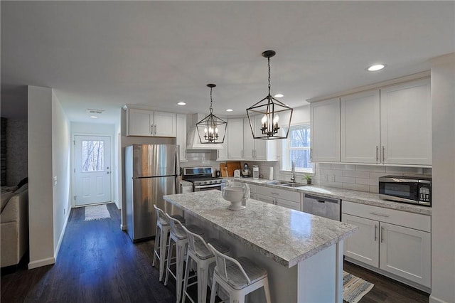 kitchen featuring white cabinets, stainless steel appliances, a kitchen island, and dark hardwood / wood-style floors