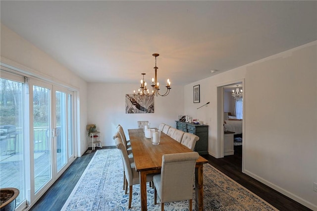 dining room with dark wood-type flooring and an inviting chandelier