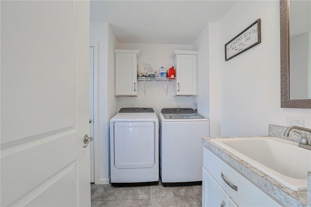 clothes washing area featuring washing machine and dryer, sink, and cabinets