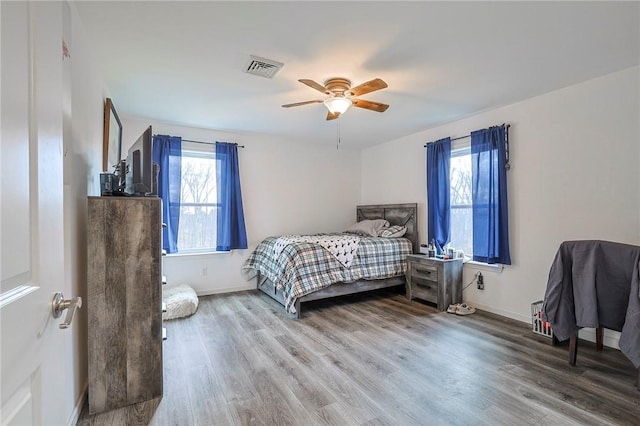 bedroom with hardwood / wood-style flooring, ceiling fan, and multiple windows