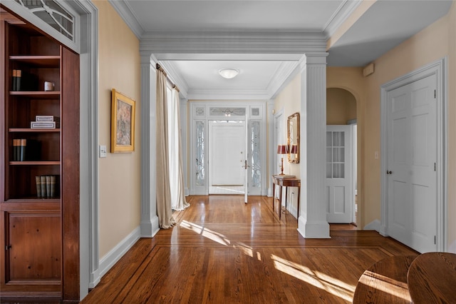 entryway featuring baseboards, arched walkways, wood finished floors, and ornamental molding