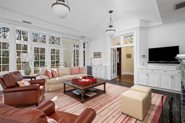 living area featuring lofted ceiling, beverage cooler, visible vents, and french doors