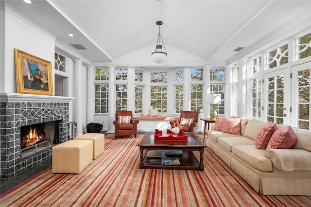 sunroom featuring vaulted ceiling, a tiled fireplace, and visible vents