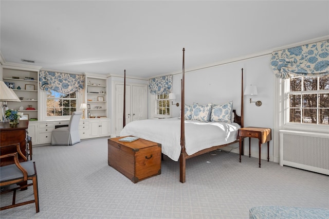 bedroom with light carpet, radiator heating unit, visible vents, and built in desk