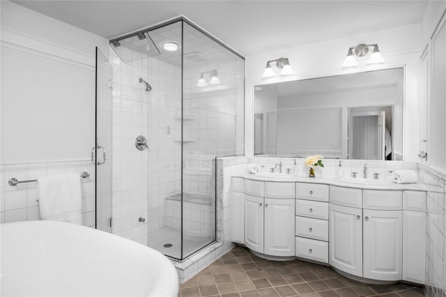 bathroom with double vanity, a stall shower, tile walls, and a sink