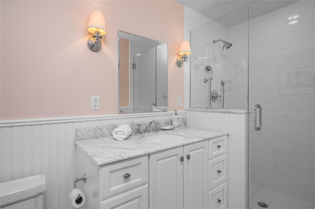 full bath with wainscoting, a shower stall, and vanity