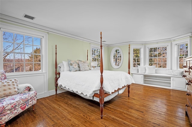 bedroom featuring ornamental molding, visible vents, baseboards, and wood finished floors