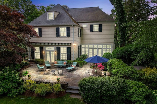 back of property featuring a shingled roof, french doors, a patio area, and an outdoor living space