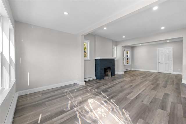 unfurnished living room with hardwood / wood-style floors and a baseboard heating unit