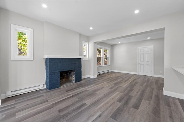 unfurnished living room with wood-type flooring, a wealth of natural light, and a baseboard heating unit