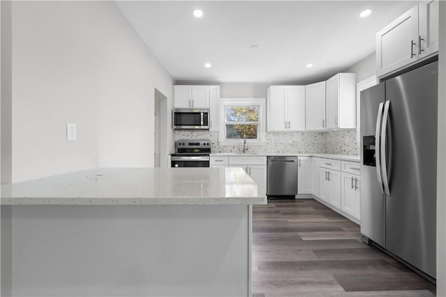 kitchen featuring white cabinets, appliances with stainless steel finishes, dark hardwood / wood-style floors, and light stone countertops