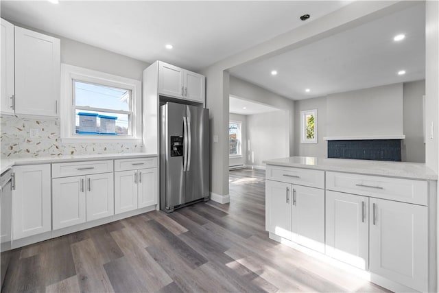 kitchen featuring appliances with stainless steel finishes, backsplash, white cabinetry, and a healthy amount of sunlight