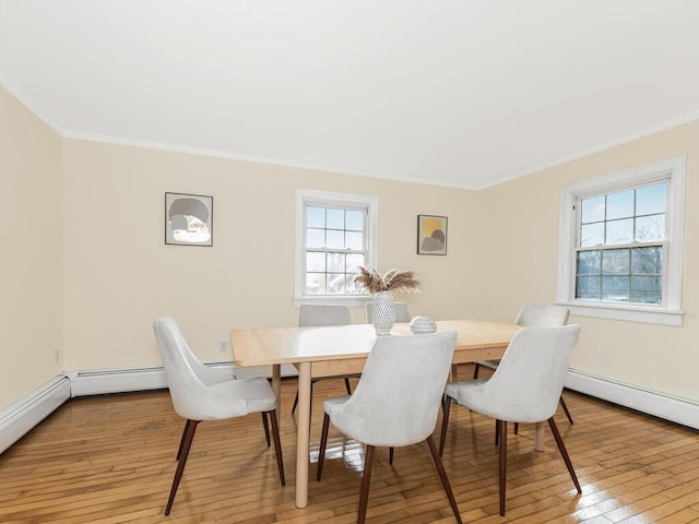 dining room featuring light hardwood / wood-style flooring, a baseboard radiator, and ornamental molding