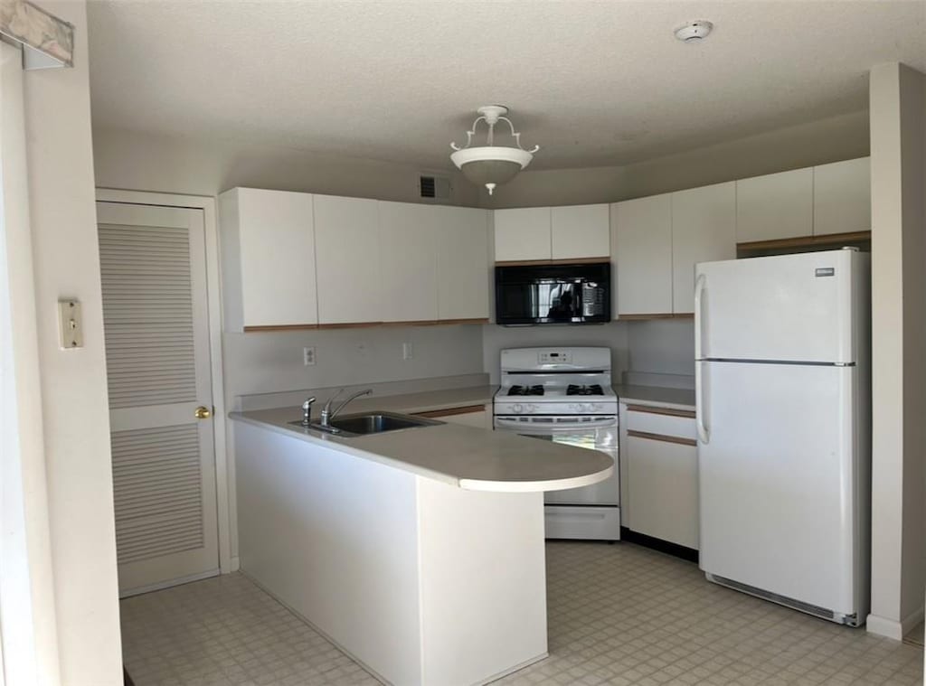 kitchen featuring white appliances, white cabinets, sink, a textured ceiling, and kitchen peninsula