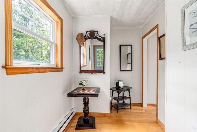 corridor with a textured ceiling, light hardwood / wood-style floors, ornamental molding, and wood walls