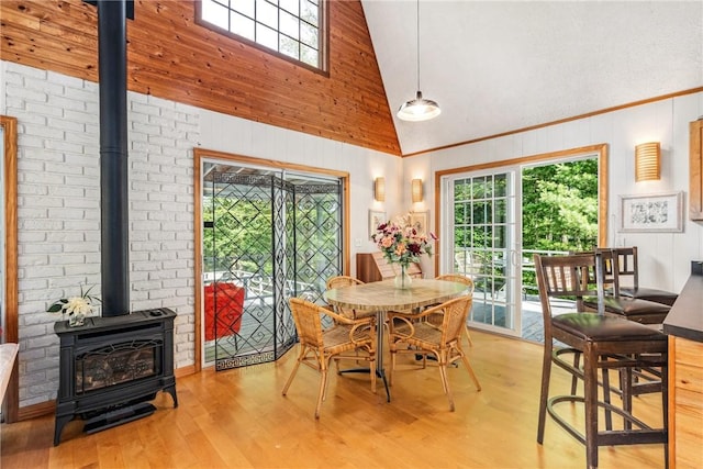 dining space with a wood stove, a healthy amount of sunlight, and light hardwood / wood-style floors