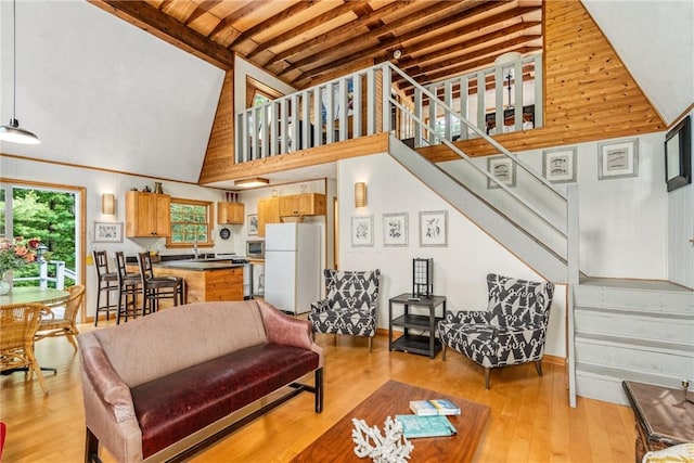 living room featuring beam ceiling, high vaulted ceiling, and light wood-type flooring