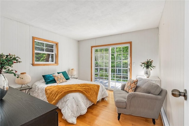 bedroom featuring access to exterior, wood-type flooring, and wood walls