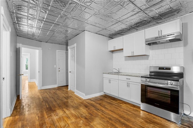 kitchen featuring white cabinets, decorative backsplash, stainless steel stove, and dark hardwood / wood-style floors