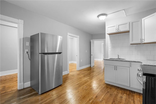 kitchen with white cabinets, wood-type flooring, stainless steel refrigerator, and sink