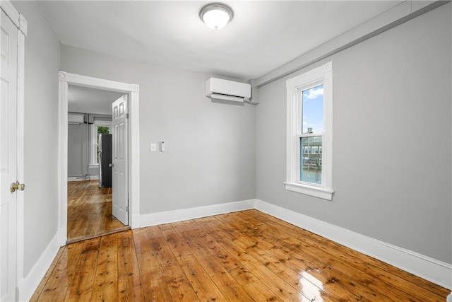 empty room featuring a wall mounted air conditioner and wood-type flooring