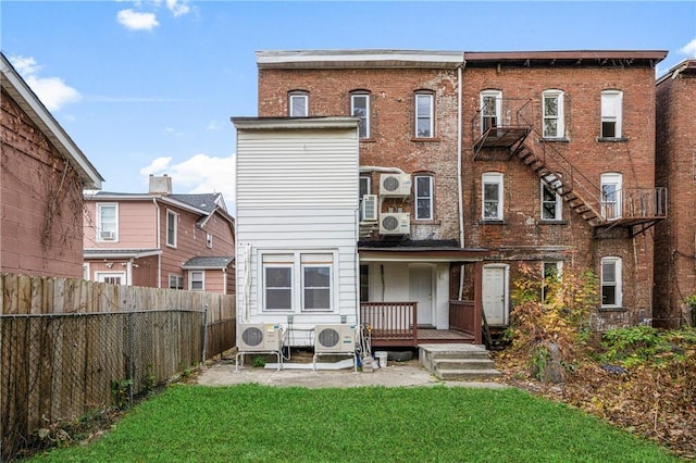 rear view of house with ac unit and a lawn