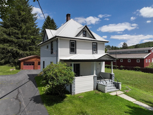 view of front of house featuring covered porch, a garage, an outdoor structure, and a front yard