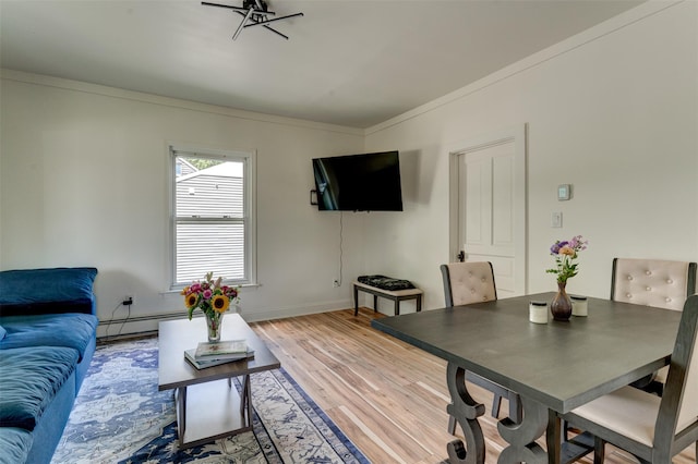 living room with wood-type flooring, a baseboard radiator, and crown molding