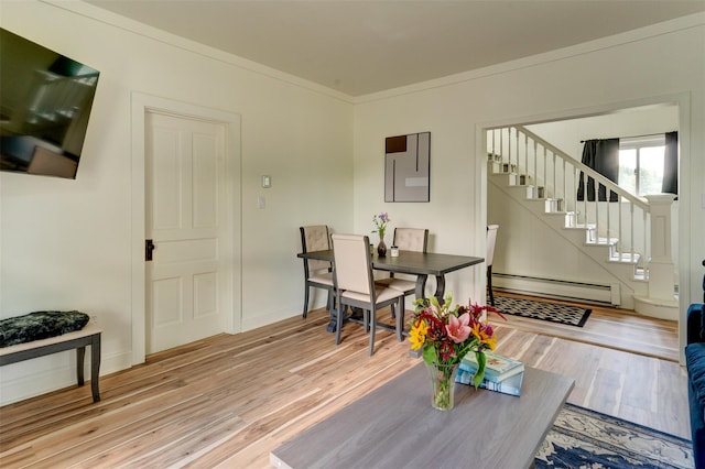 dining room with hardwood / wood-style floors, crown molding, and a baseboard heating unit