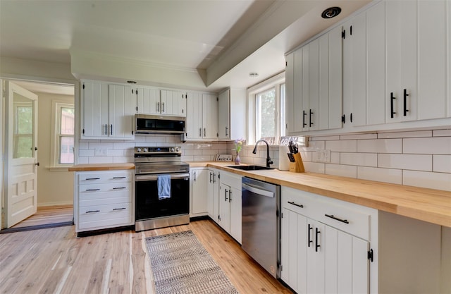 kitchen featuring white cabinetry, sink, light hardwood / wood-style flooring, and appliances with stainless steel finishes