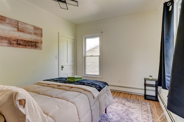 bedroom featuring crown molding, light hardwood / wood-style floors, and a baseboard radiator