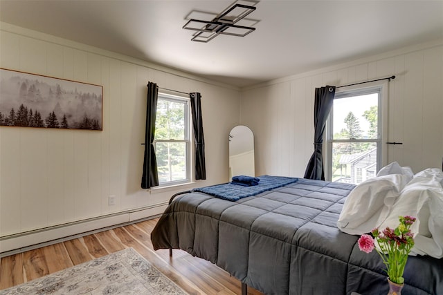 bedroom featuring hardwood / wood-style flooring, a baseboard radiator, and multiple windows