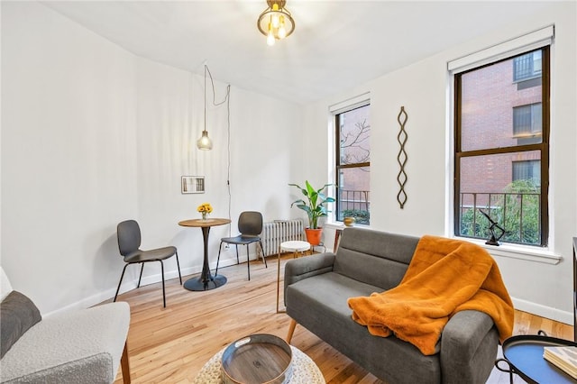 sitting room with radiator heating unit, baseboards, and wood finished floors