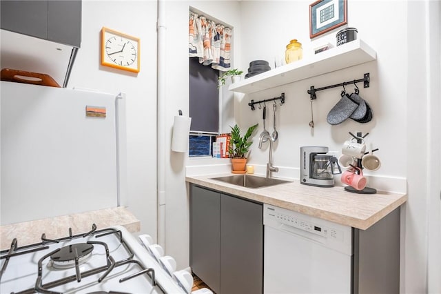 interior space with white appliances, gray cabinets, a sink, and light countertops