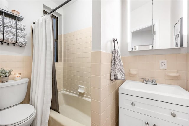 full bath with toilet, vanity, tile walls, wainscoting, and shower / tub combo with curtain