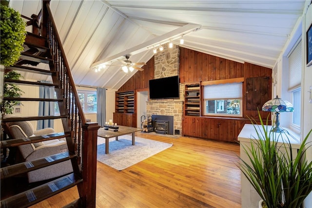 living room with a wood stove, light wood-type flooring, vaulted ceiling, and wood walls