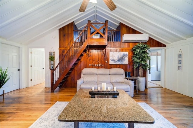 living room with a wall mounted air conditioner, wood walls, lofted ceiling with beams, hardwood / wood-style flooring, and ceiling fan