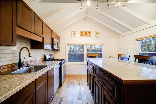 kitchen featuring a kitchen breakfast bar, backsplash, stainless steel appliances, sink, and light hardwood / wood-style flooring