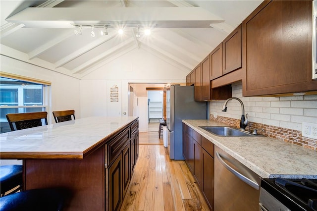 kitchen with sink, lofted ceiling with beams, light wood-type flooring, a breakfast bar area, and appliances with stainless steel finishes