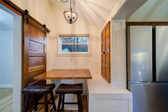 dining space with a barn door, lofted ceiling, and a notable chandelier