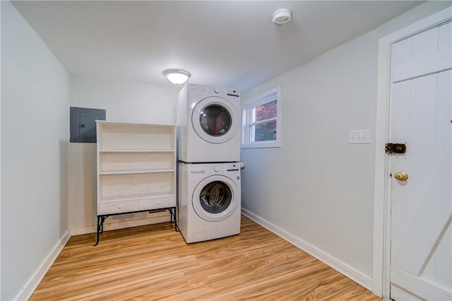 clothes washing area featuring electric panel, stacked washer / drying machine, and light wood-type flooring