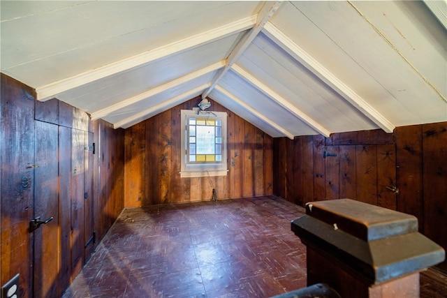 bonus room with vaulted ceiling and wood walls