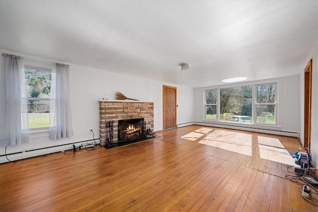 unfurnished living room with a brick fireplace, light hardwood / wood-style floors, and a baseboard radiator