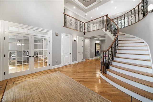 entrance foyer featuring hardwood / wood-style floors, a towering ceiling, and french doors