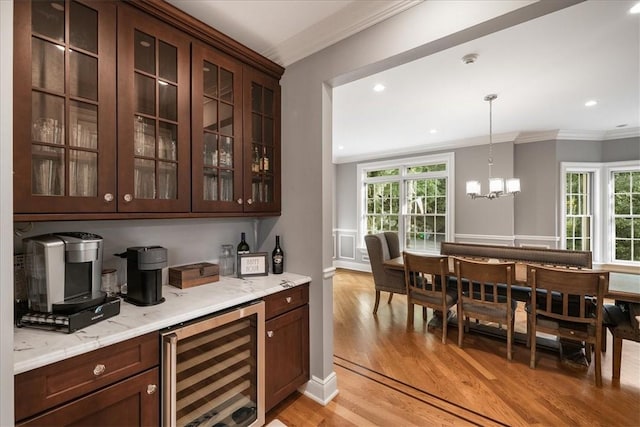 bar featuring light hardwood / wood-style floors, light stone counters, beverage cooler, and a healthy amount of sunlight