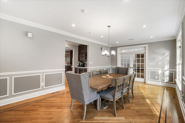 dining area featuring french doors, light hardwood / wood-style flooring, ornamental molding, and a notable chandelier