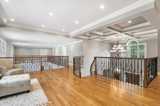 interior space with beam ceiling, coffered ceiling, light hardwood / wood-style flooring, crown molding, and a chandelier