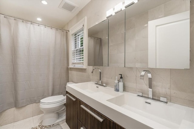 bathroom featuring tile patterned floors, vanity, tile walls, and toilet