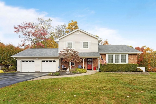 traditional home with aphalt driveway, an attached garage, brick siding, and a front lawn