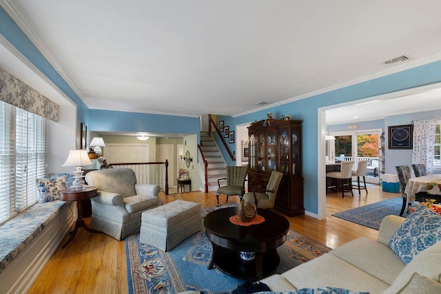 living room featuring visible vents, baseboards, stairway, ornamental molding, and wood finished floors